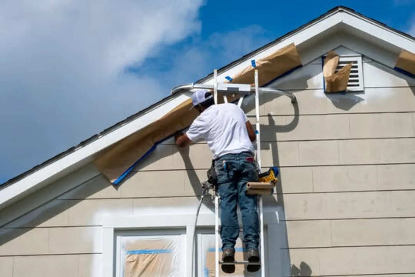 Painter masking and prepping a home exterior before painting