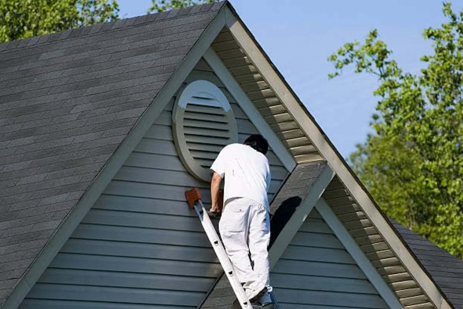 Professional painter on a ladder painting a home gable